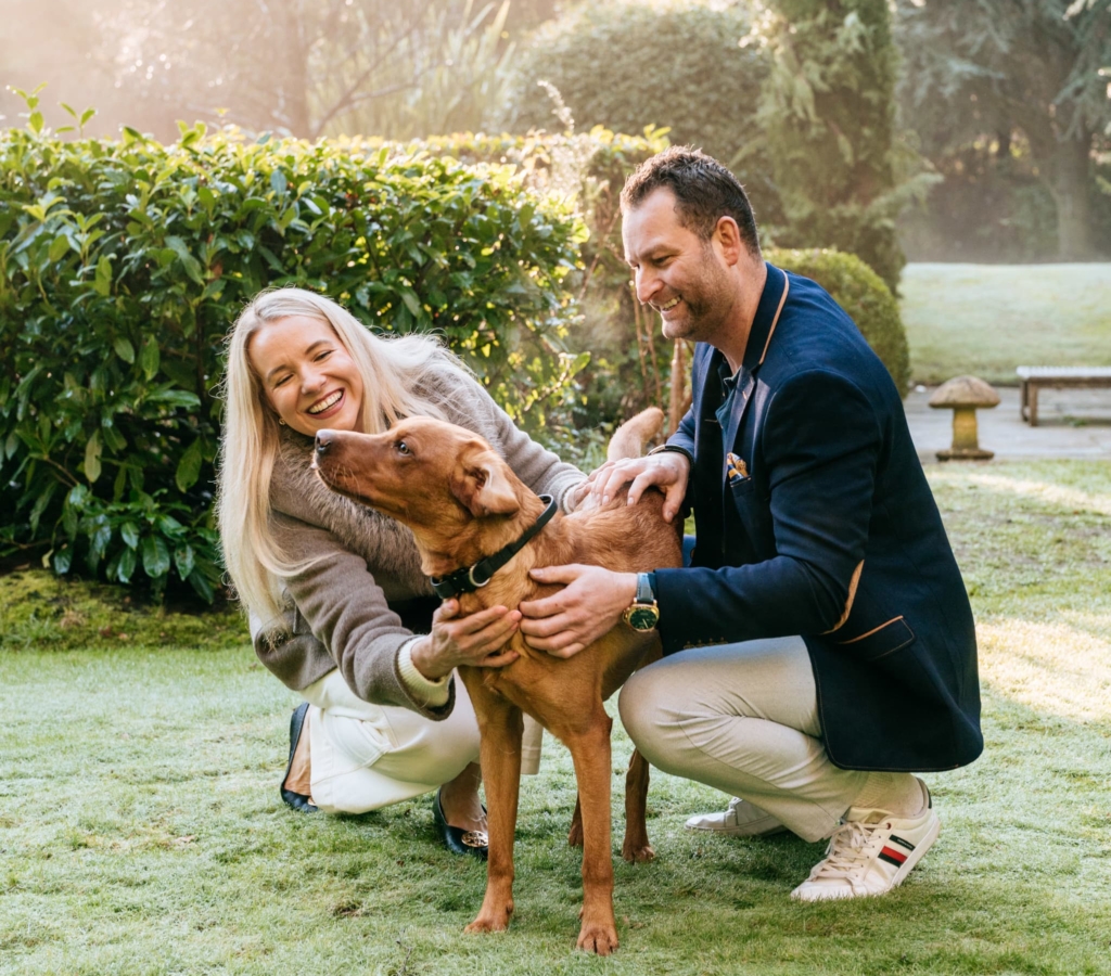 Couple playing with trained dog outdoors