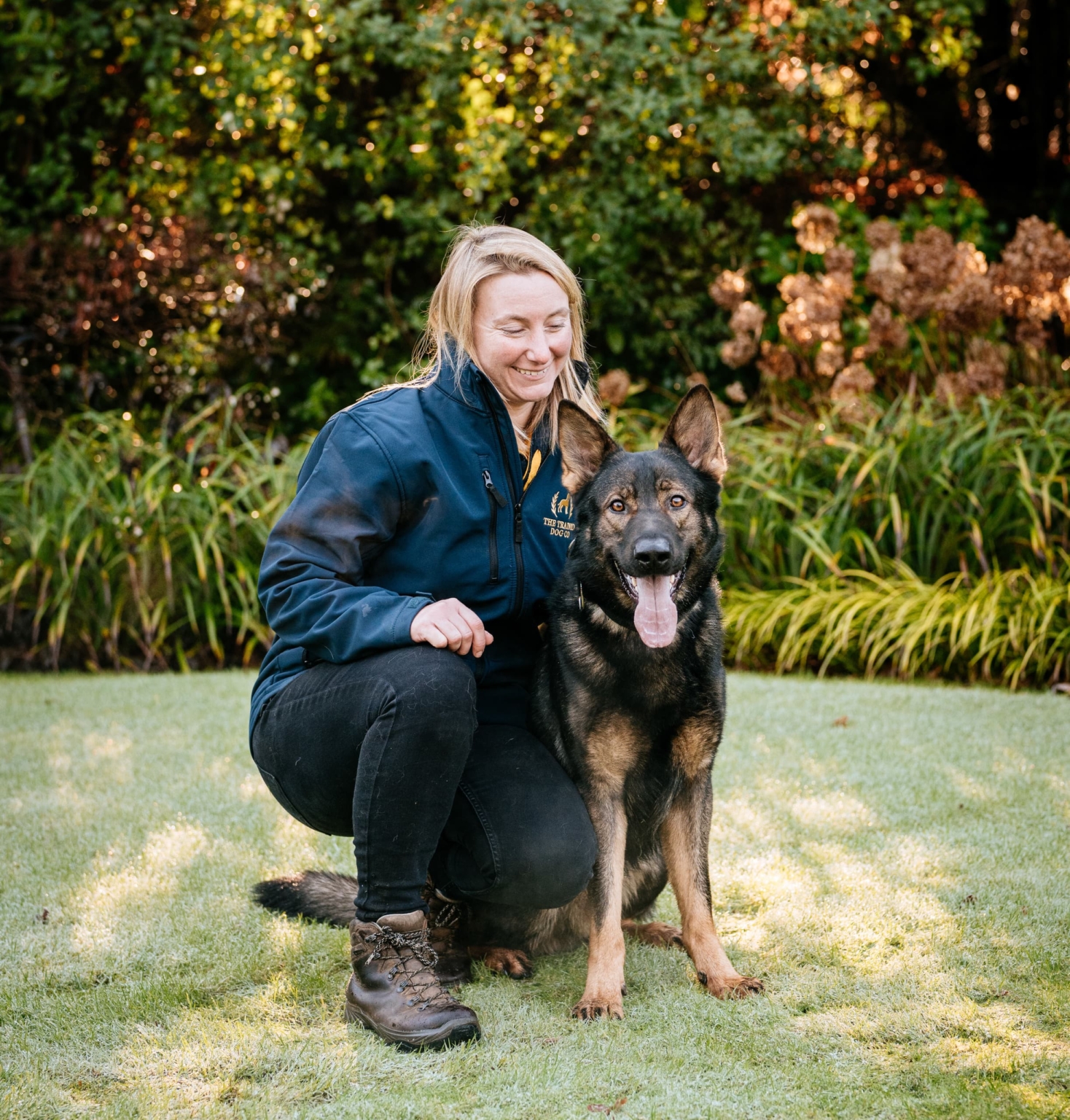 Trainer kneeling beside trained dog
