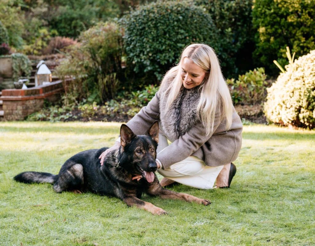 Woman sitting and stroking trained dog outdoors