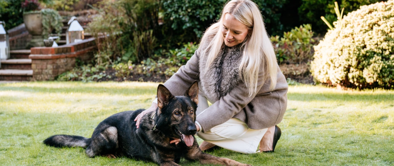 Woman sitting and stroking trained dog outdoors