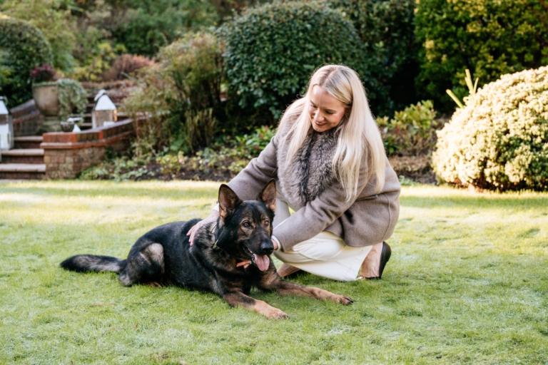 Woman sitting and stroking trained dog outdoors